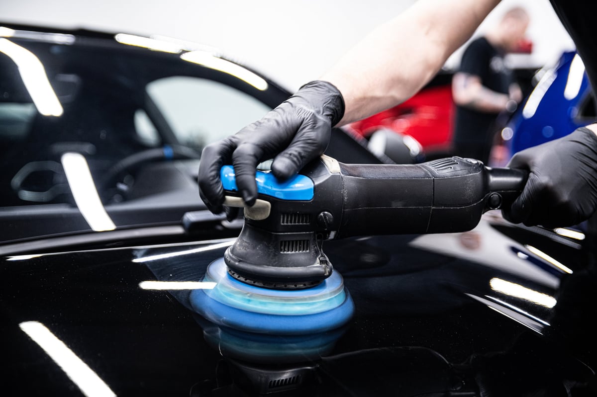 Gloved detailer machine-polishing car paint