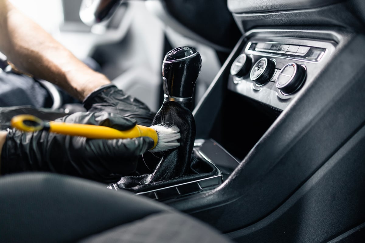Detailer brushing dust from a car interior