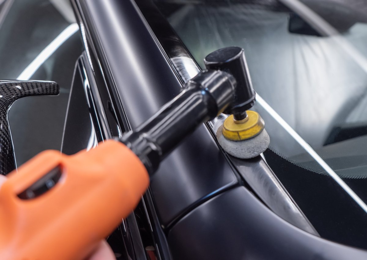 Repairman polishing a car fender with a machine