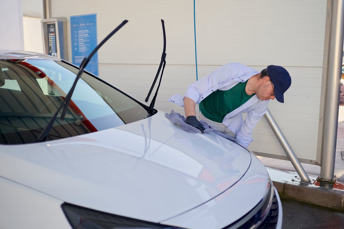 Drying a car hood with a microfiber cloth