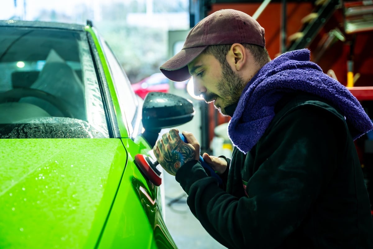 Technician polishing a vibrant green car